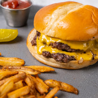 Cheesy wagyu smash burger with fries on a gray surface