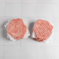 Two stacks of smash burger patties on a white tiled surface