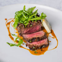 cooked and sliced filet mignon on plate with butter sauce and greens |lifestyle