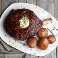 Cooked cowboy steak on plate with potatoes 