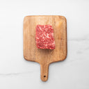 Wooden cutting board with a piece of marbled red meat on a white background