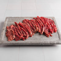 Raw beef on a stone cutting board with a tiled floor background