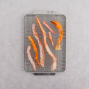 Raw Alaskan golden king crab legs on a metal grilling rack, preparing for cooking.