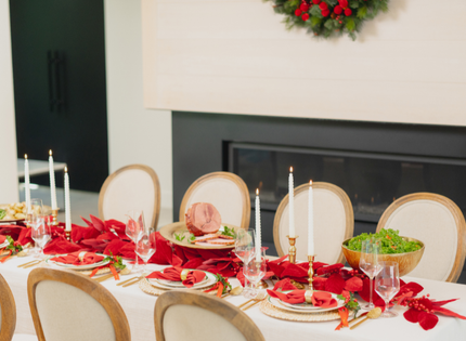 a holiday table setting with a ham, candles, salad, with a fireplace behind. 