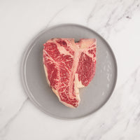 raw dry-aged porterhouse steak on plate