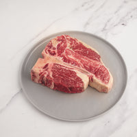 raw dry-aged porterhouse steak on plate 