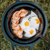 Fried eggs and bacon in a cast iron skillet on a natural background