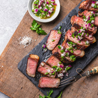 Cooked and sliced NY strip steak with chimichurri 