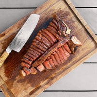 cooked Prime Porterhouse Steak sliced on cutting board 