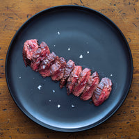 cooked and sliced hanger steak on plate with finishing salt 