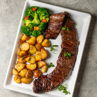 Cooked USDA Skirt Steak on plate with vegetables