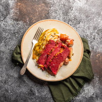 cooked sliced corned beef on a plate with veggies 