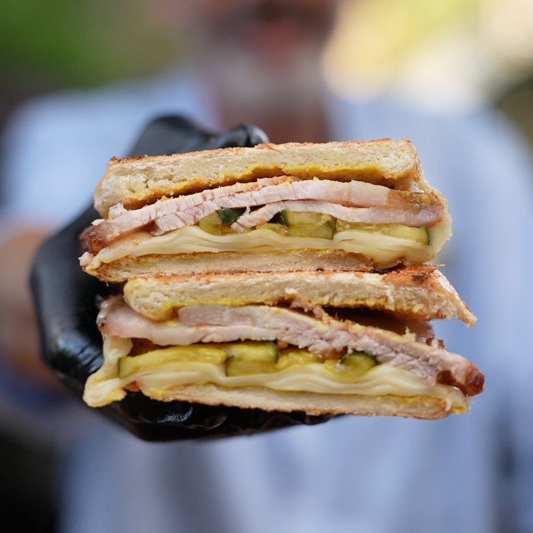 Stack of a layered sandwich held by a person wearing a black glove with a blurred background