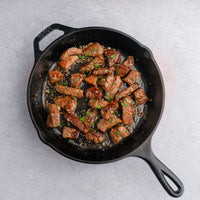 Cooked dry-aged steak cuts in cast iron skillet 