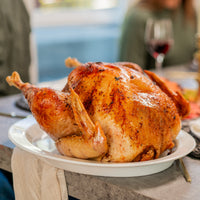 Roasted turkey on a plate with a blurred background of people and a table.