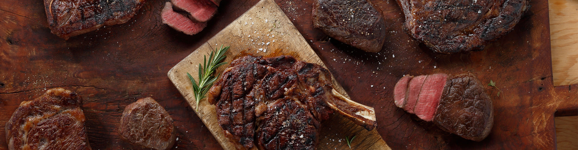 An assortment of cooked steaks on a cutting board