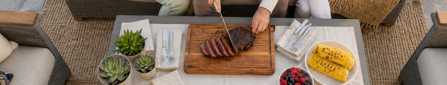 Ribeye Steak being sliced on a cutting board with corn and fruit on the side