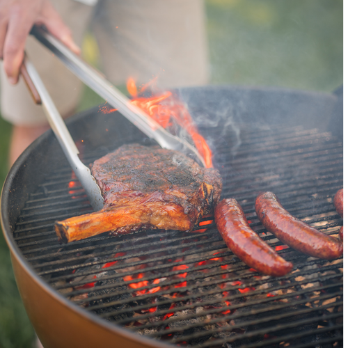 Wagyu Cowboy steak on a grill with sausages