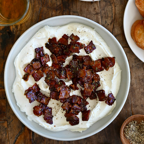 Bowl of creamy dip with crumbled bacon on a wooden table