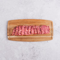Sliced raw beef on a wooden cutting board with a light gray background