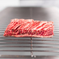 Raw Gold Plus skirt steak on a metal rack with a blurred background