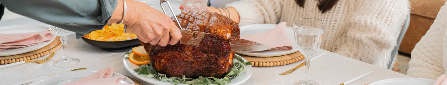 A roasted glazed kurobuta ham being sliced on a table