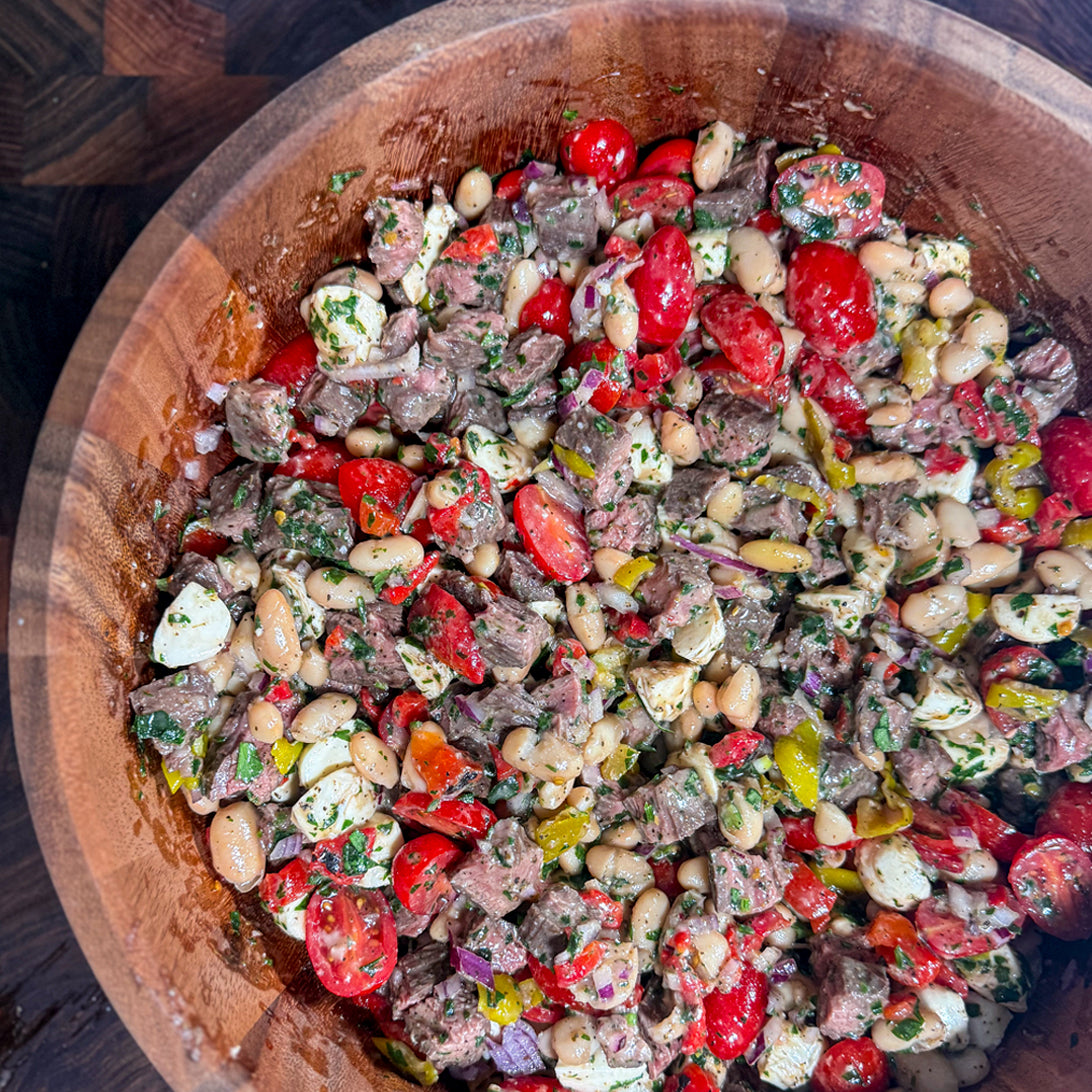 Colorful Italian steak salad with beans and tomatoes in a wooden bowl