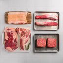 Assorted fresh meats including two packages of ground beef, a flank steak, pork tenderloin, bacon, and tri-tip.