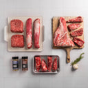 Raw meat on cutting boards and trays with seasonings on a tiled surface