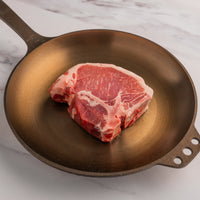 raw pork porterhouse in cast iron skillet 