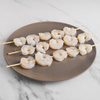 Shrimp on wooden skewers placed on plate.