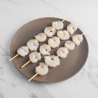 Shrimp on wooden skewers placed on plate.