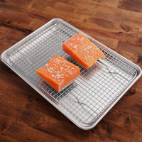 Two salmon filets on metal sheet pan with grate and salt sprinkled on top.