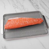 Salmon filet on metal sheet pan and grate with salt sprinkled on it.