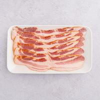 Raw Apple Brined Uncured Bacon on white plate 