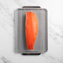 Raw salmon fillet on a metal grill rack over a marble countertop