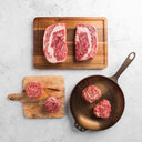 A collection of thick-cut American Wagyu steaks of various shapes and sizes, displaying a rich marbled texture.
