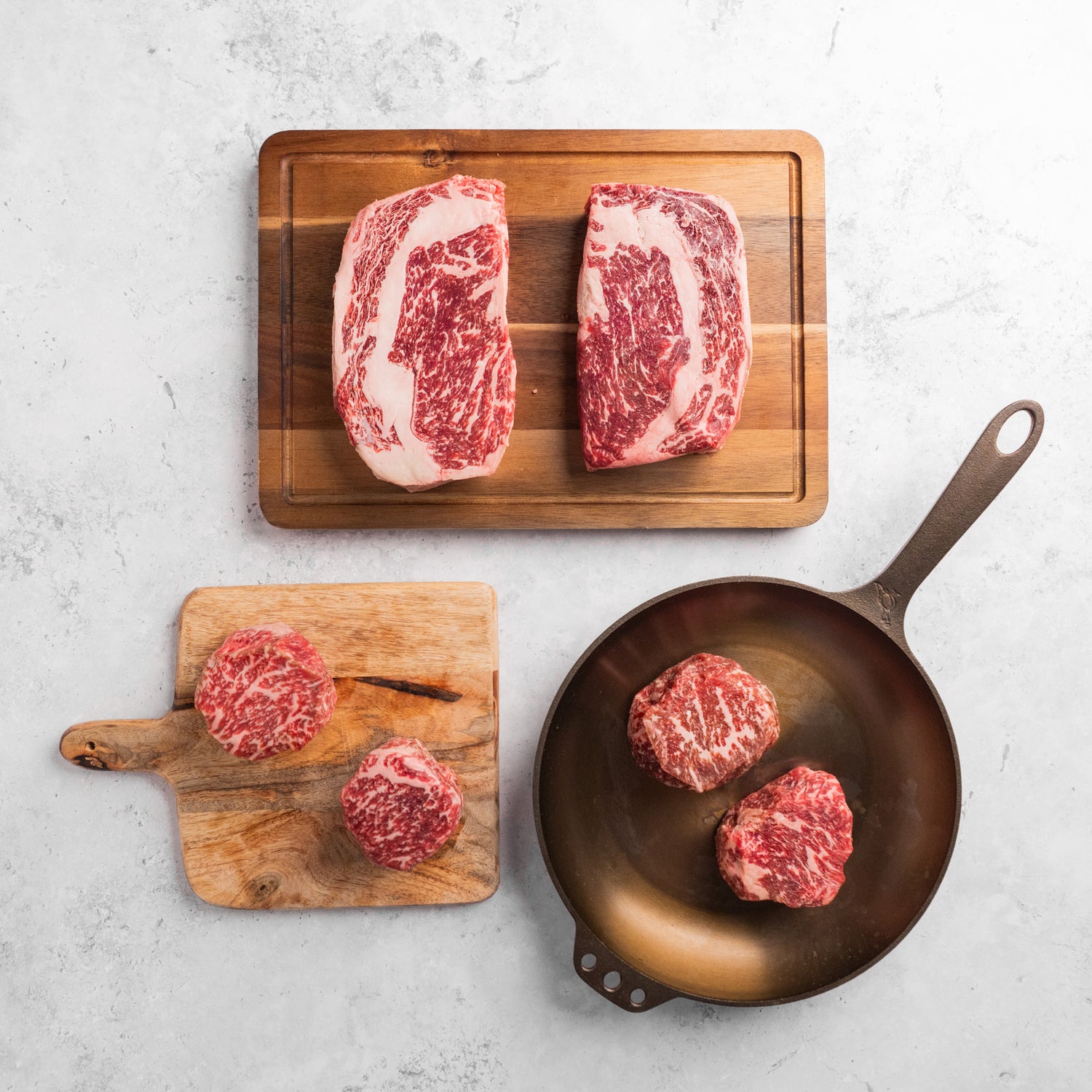 A collection of thick-cut American Wagyu steaks of various shapes and sizes, displaying a rich marbled texture.