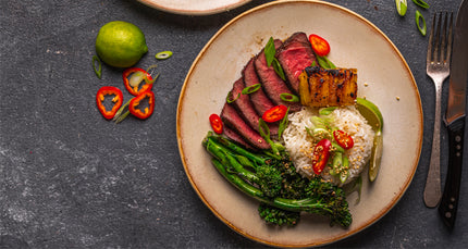 Plated dish with steak, vegetables, and rice on a dark surface