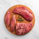Raw beef steaks on a wooden cutting board with thyme leaves on a marble background