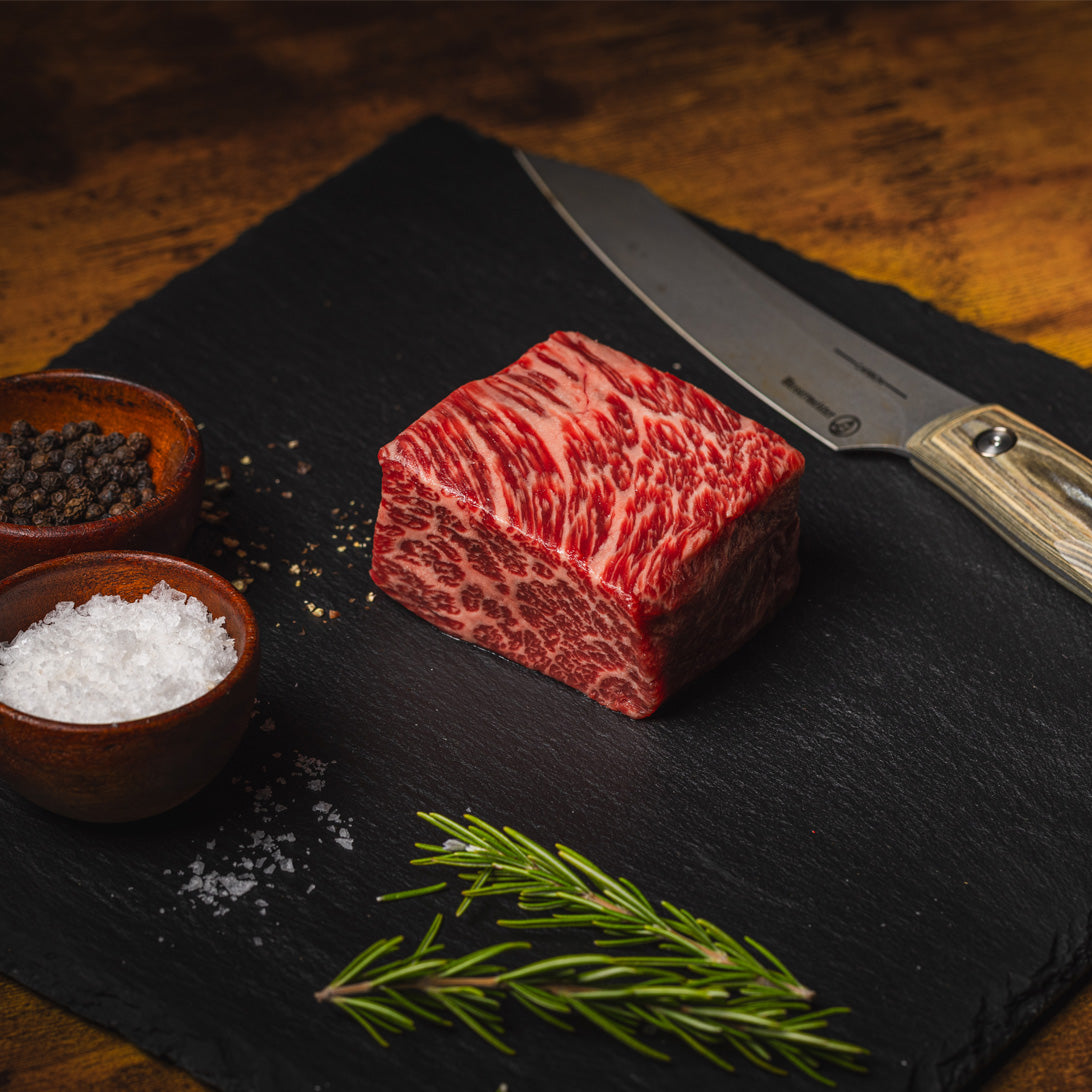 Raw Gold Plus Wagyu Zabuton Block on dark board with seasoning and knife