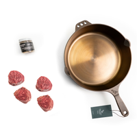 Cast Iron frying pan with raw meat and seasoning on a white background