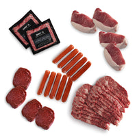 Assorted cuts of raw meat including steaks and sausages on a white background.