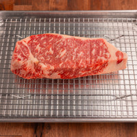 USDA Prime NY strip steak on rack and pan 