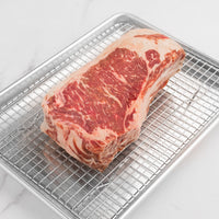 raw Delmonico steak on rack and pan 