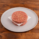 two raw wagyu burger patties on a white plate 