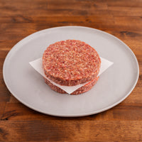 two raw wagyu burger patties on a white plate 