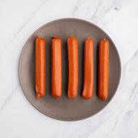 raw whole hot dogs on a plate 