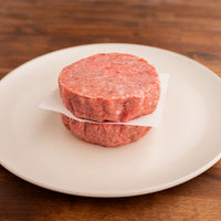 two raw burger patties on white plate 