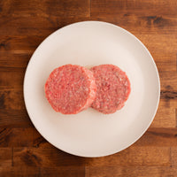 two raw burger patties on white plate 